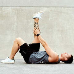 man stretching hamstring or thigh muscle after workout